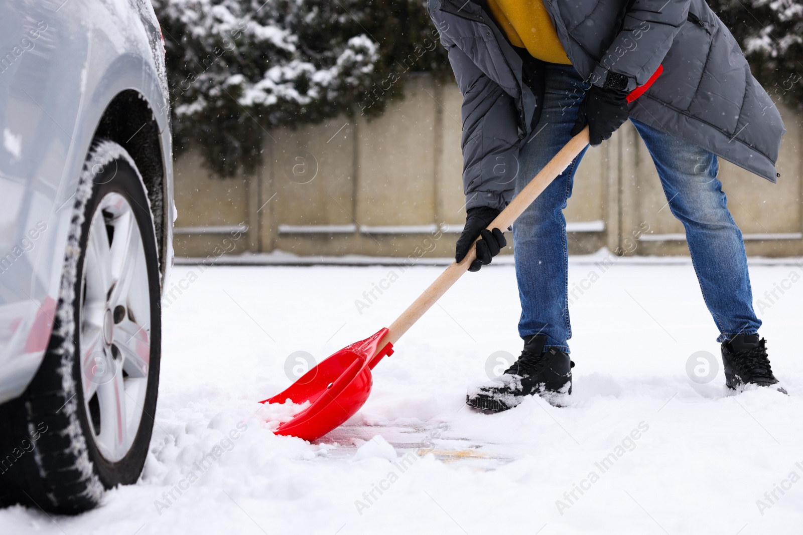 Photo of Man removing snow with shovel near car outdoors, closeup