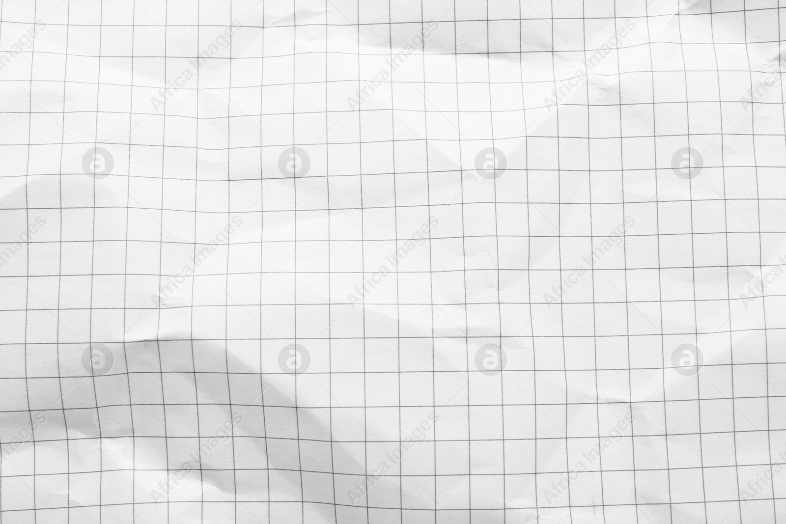 Photo of Crumpled checkered notebook sheet as background, top view