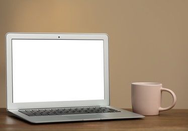 Photo of Laptop with blank screen on table indoors. Space for text