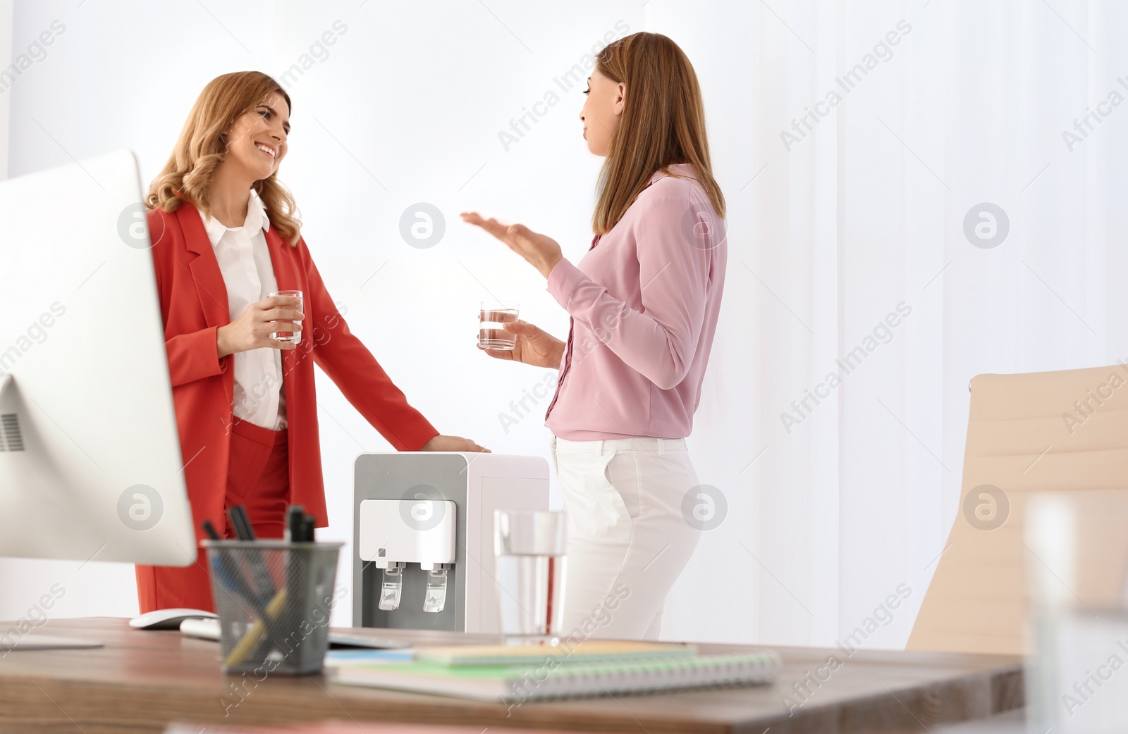 Photo of Women having break near water cooler at workplace