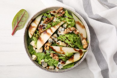 Photo of Delicious pear salad with sauce in bowl on light table, top view