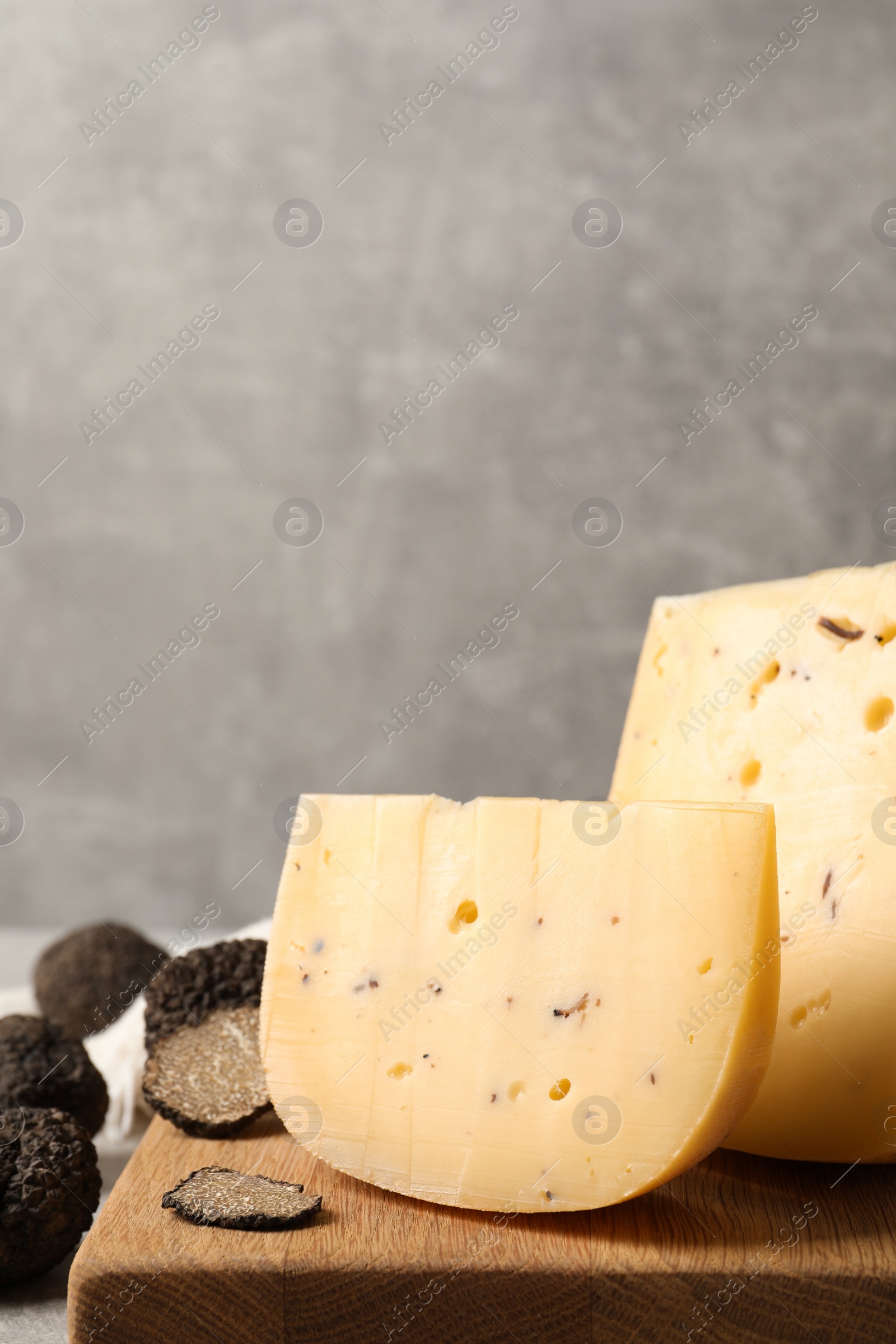 Photo of Delicious cheese and fresh black truffles on table. Space for text