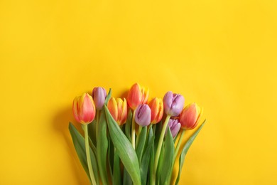 Photo of Many beautiful tulips on yellow background, flat lay. Space for text