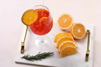 Photo of Glass of tasty Aperol spritz cocktail with orange slices and rosemary on white table, above view