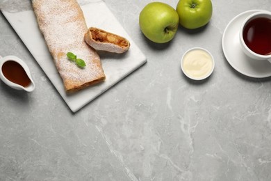 Photo of Delicious strudel with tasty filling served on light grey marble table, flat lay. Space for text