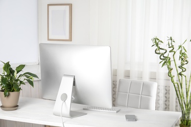 Photo of Office interior with houseplants and computer monitor on table