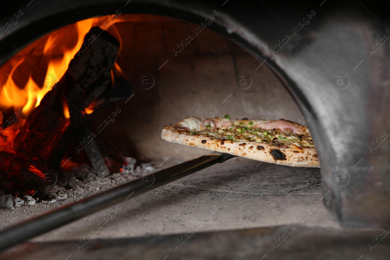 Photo of Taking out tasty pizza from oven in restaurant kitchen