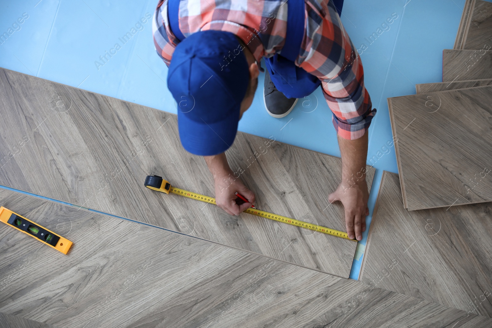 Photo of Worker installing laminated wooden floor indoors, above view