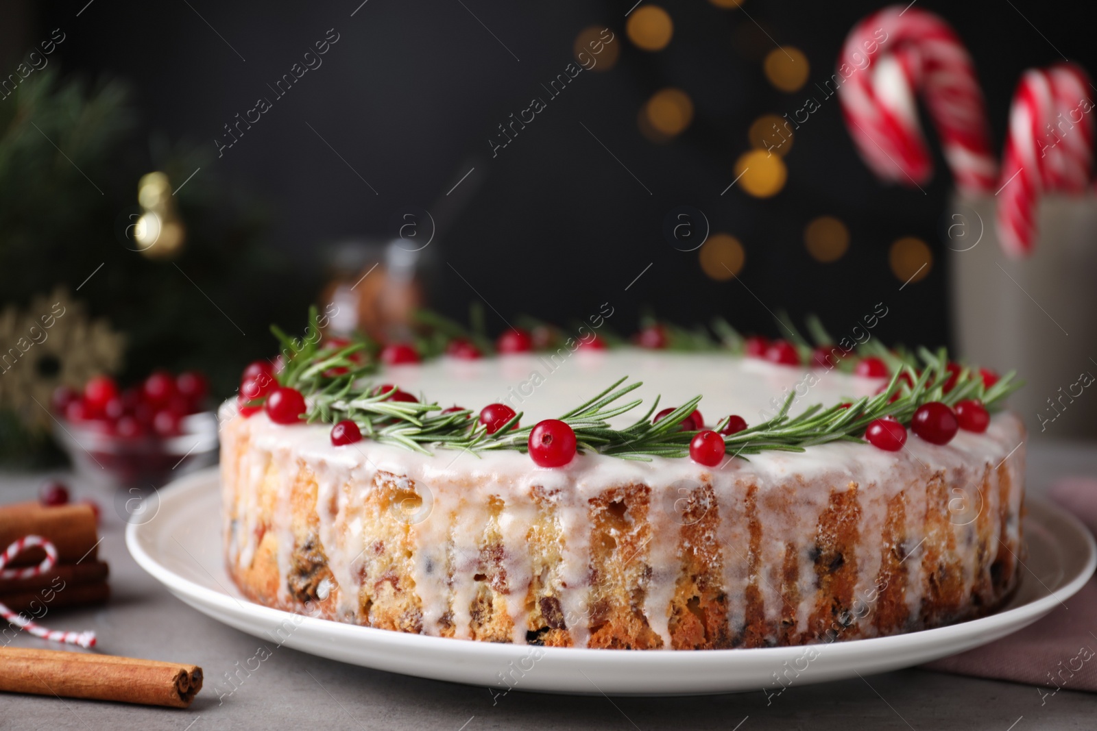 Photo of Traditional Christmas cake decorated with rosemary and cranberries on table, closeup