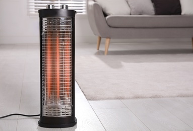 Photo of Modern electric heater on floor at home. Space for text