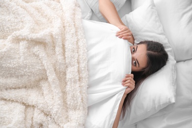 Photo of Young beautiful woman hiding under blanket in bed at home. Sleeping time
