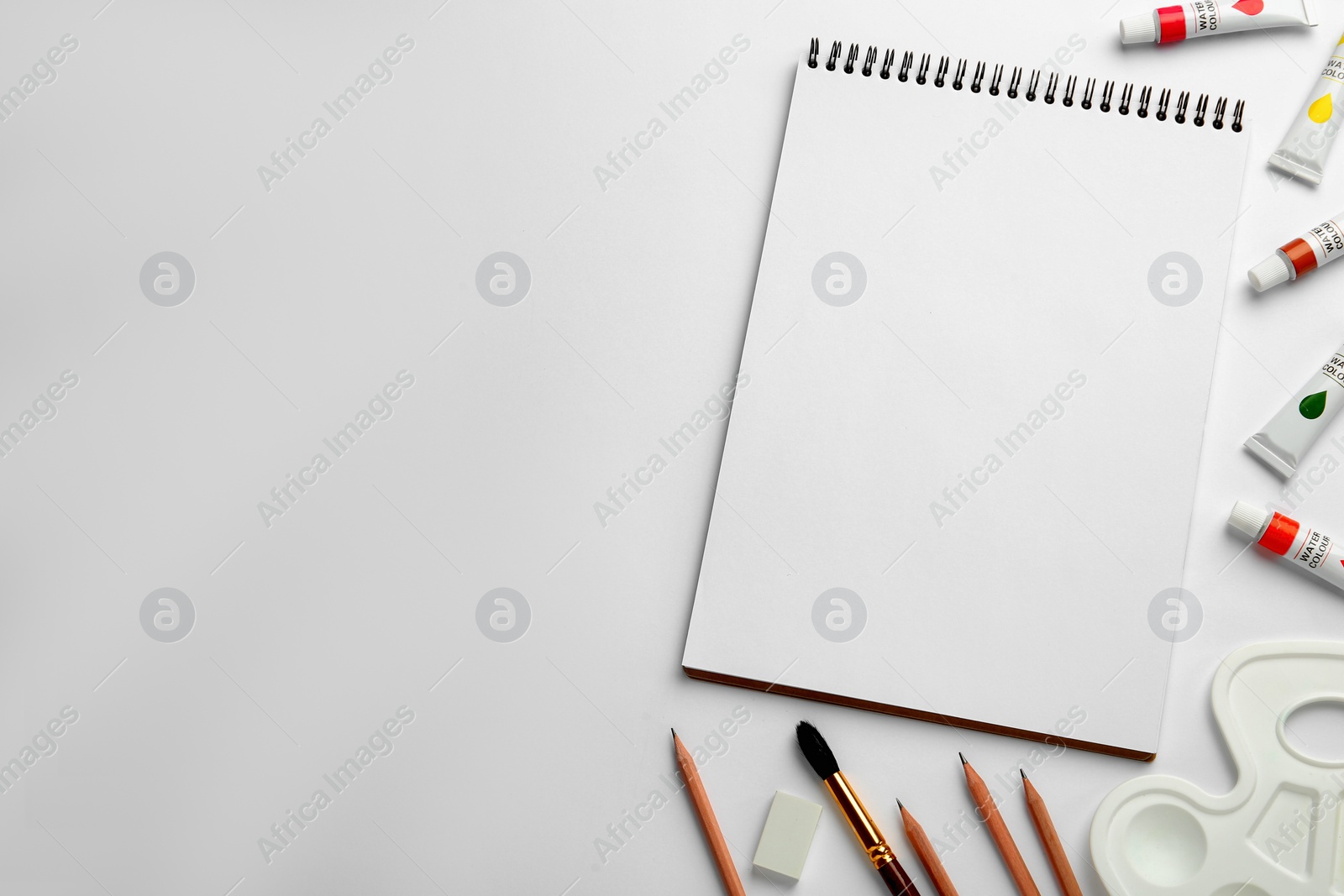 Photo of Composition with sketchbook and drawing tools on white background, top view. Space for text