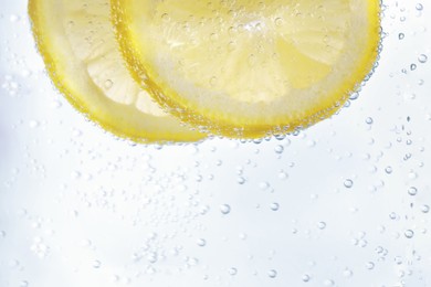 Juicy lemon slices in soda water, closeup