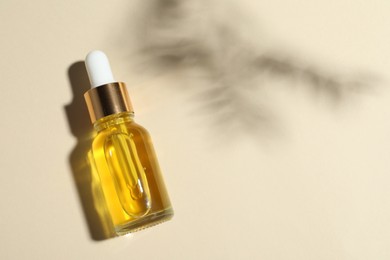 Bottle of cosmetic oil on beige background, top view. Space for text