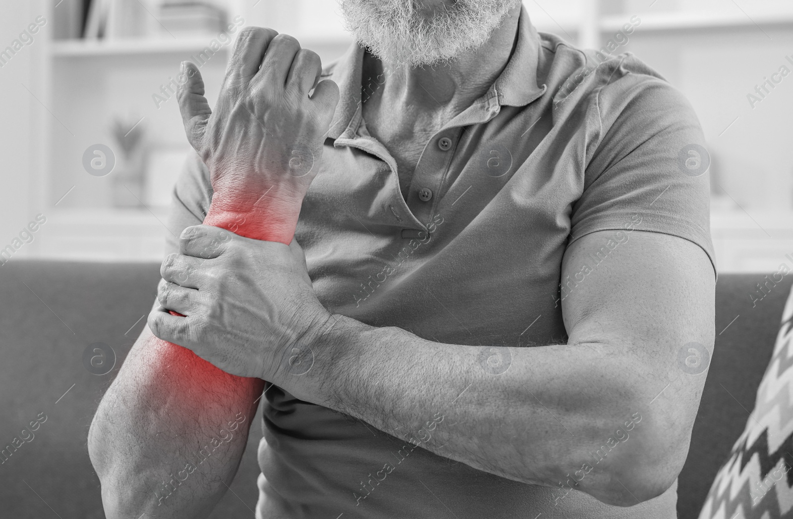 Image of Man suffering from pain in arm indoors, closeup. Black and white effect