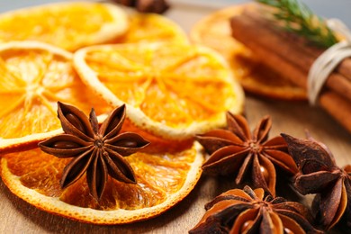 Photo of Dry orange slices and anise stars on wooden board, closeup