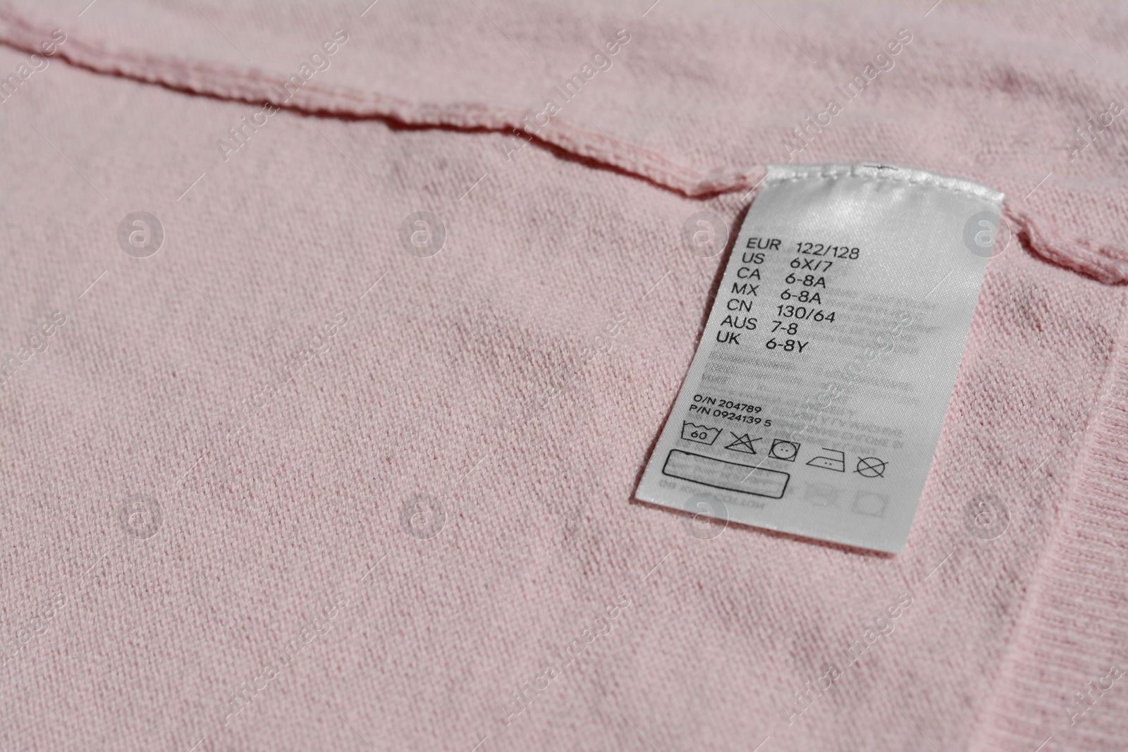 Photo of Clothing label with instruction on pink garment, closeup
