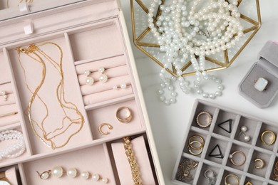 Photo of Jewelry boxes with many different accessories on white marble table, flat lay