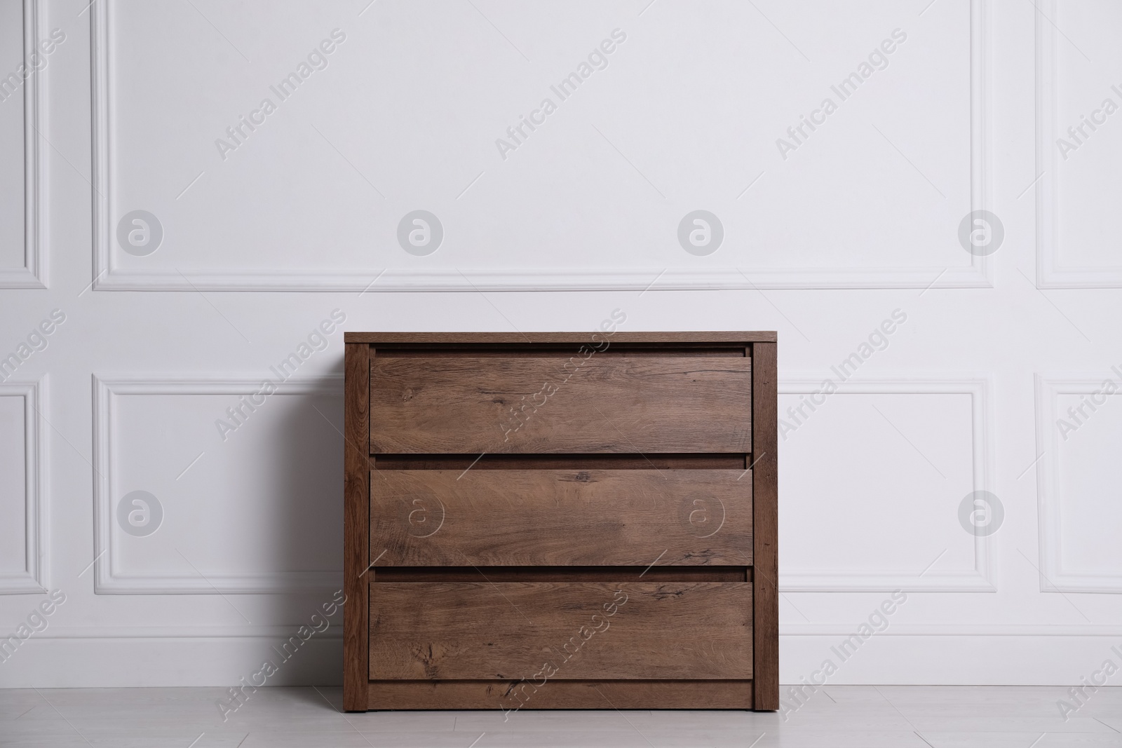 Photo of Wooden chest of drawers near white wall indoors