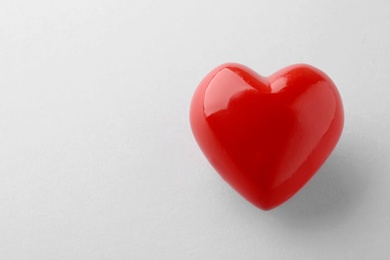 Photo of Shiny red heart on white background, top view