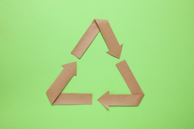 Recycling symbol cut out of paper on green background, top view