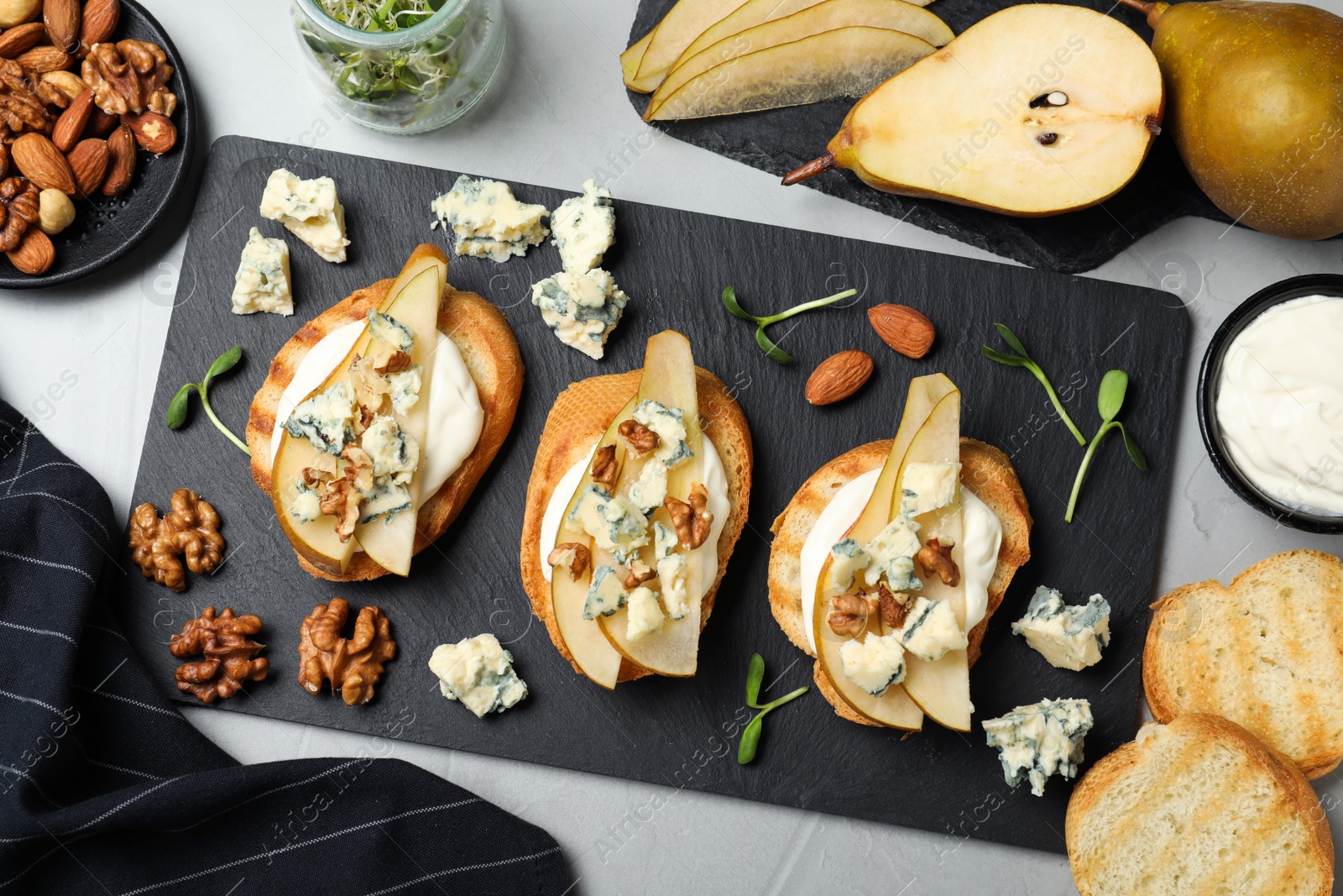 Photo of Delicious bruschettas with cheese, pear and nuts on grey table, flat lay