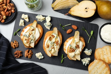 Delicious bruschettas with cheese, pear and nuts on grey table, flat lay