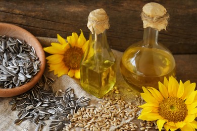 Photo of Bottles of sunflower oil, seeds and flowers on wooden table