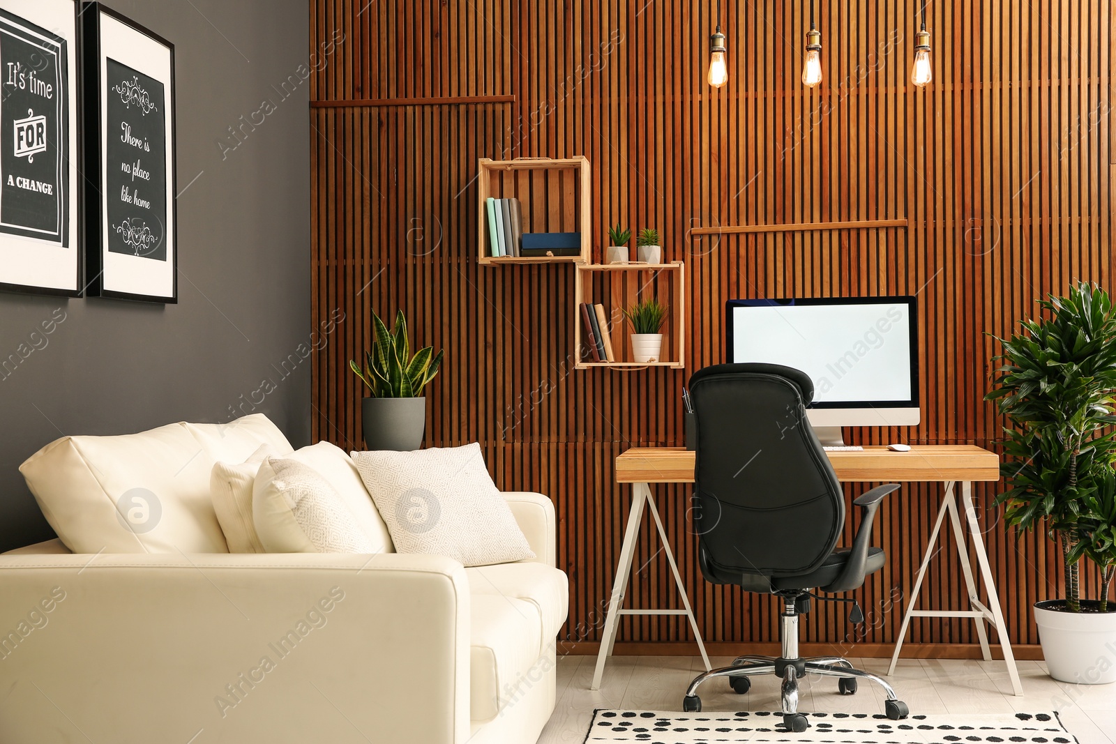 Photo of Comfortable workplace with computer near wooden wall in stylish room interior. Home office design