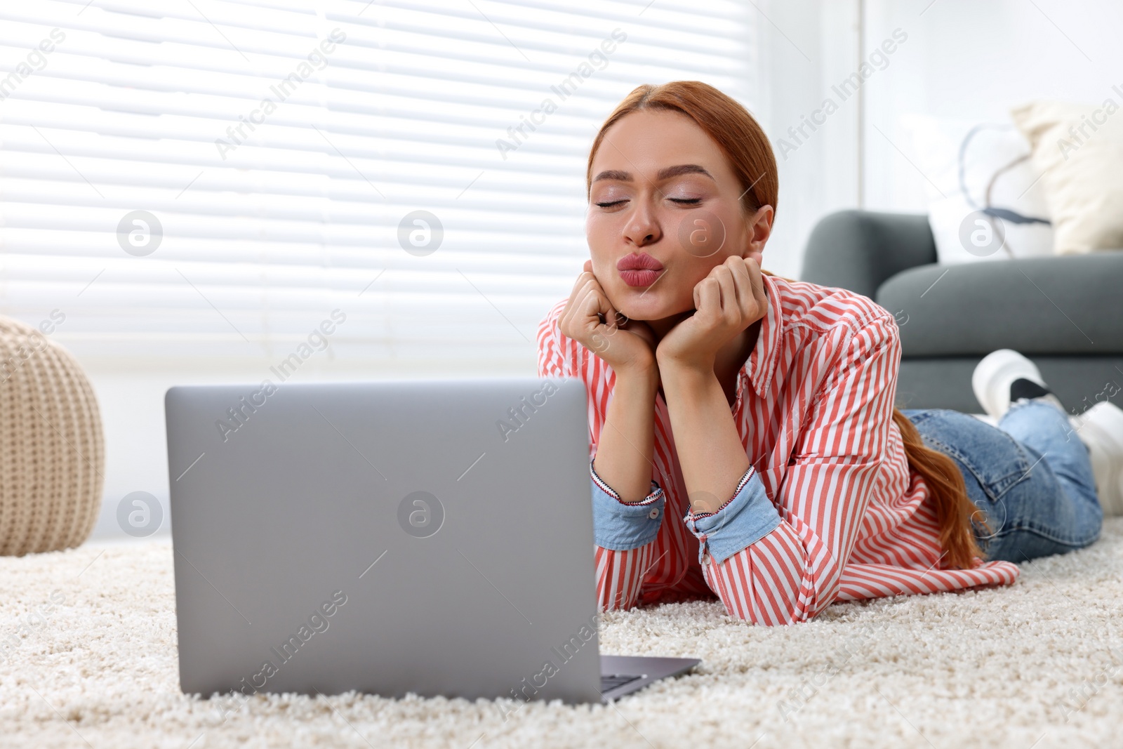 Photo of Woman blowing kiss during video chat via laptop at home. Long-distance relationship