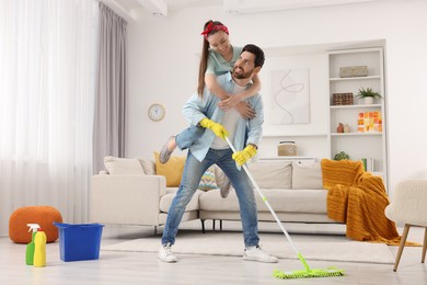 Photo of Spring cleaning. Couple having fun while tidying up living room