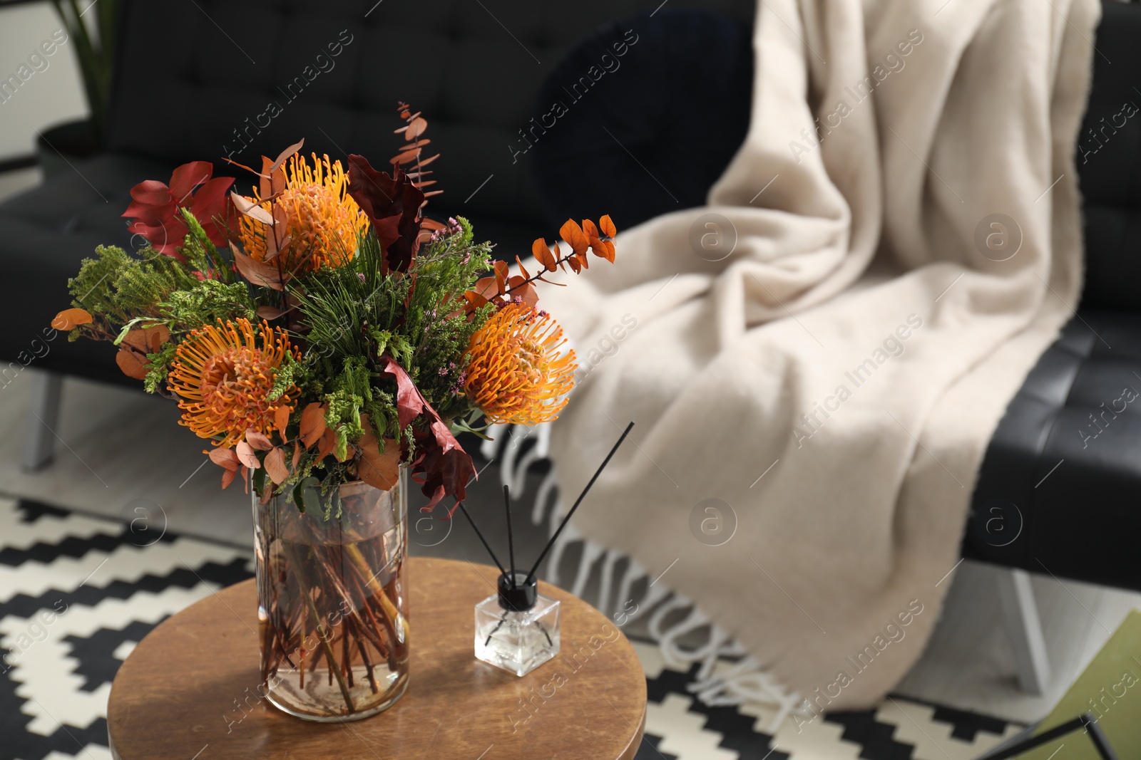 Photo of Vase with bouquet of beautiful leucospermum flowers and air freshener on side table in room, space for text