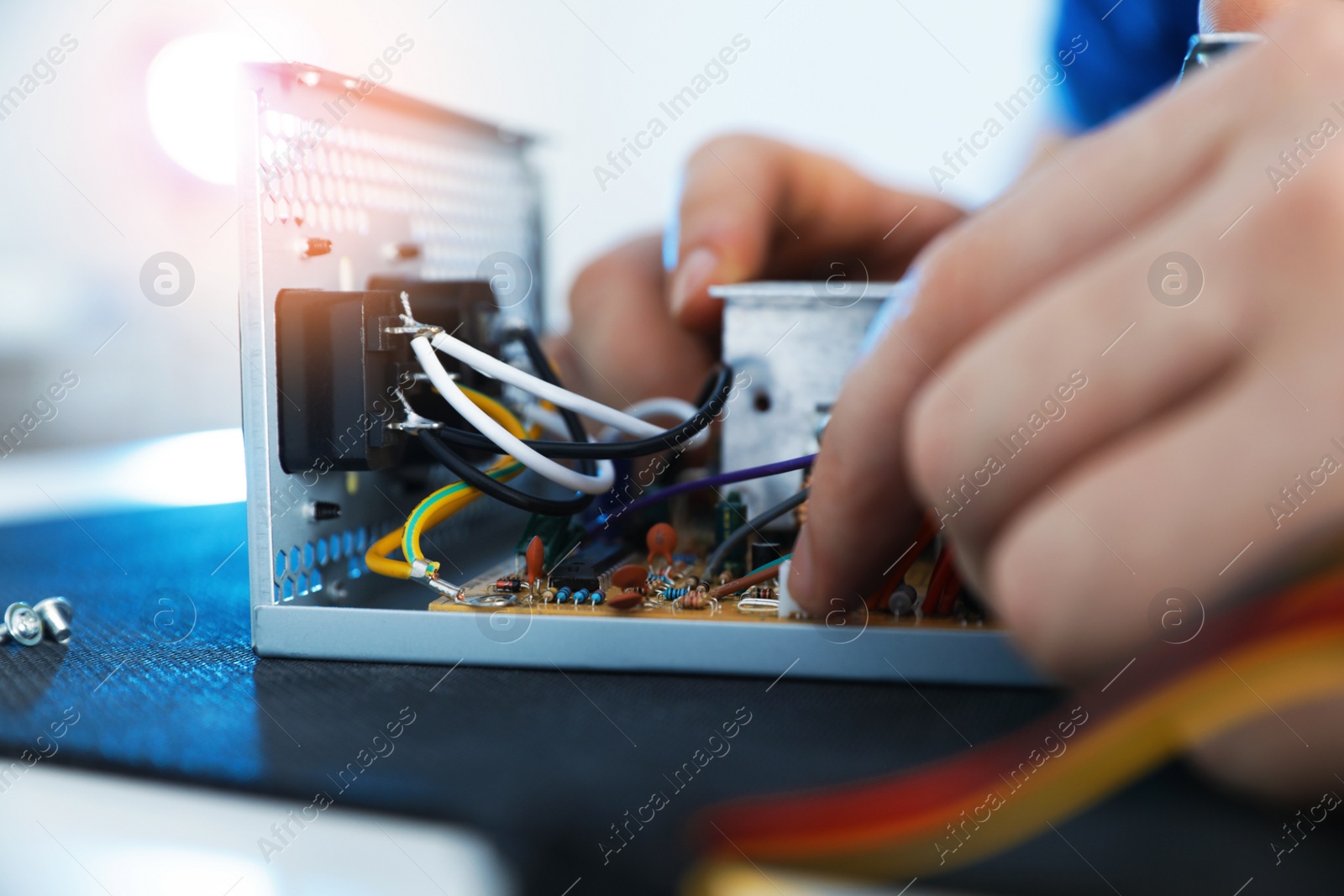 Photo of Male technician repairing power supply unit at table, closeup