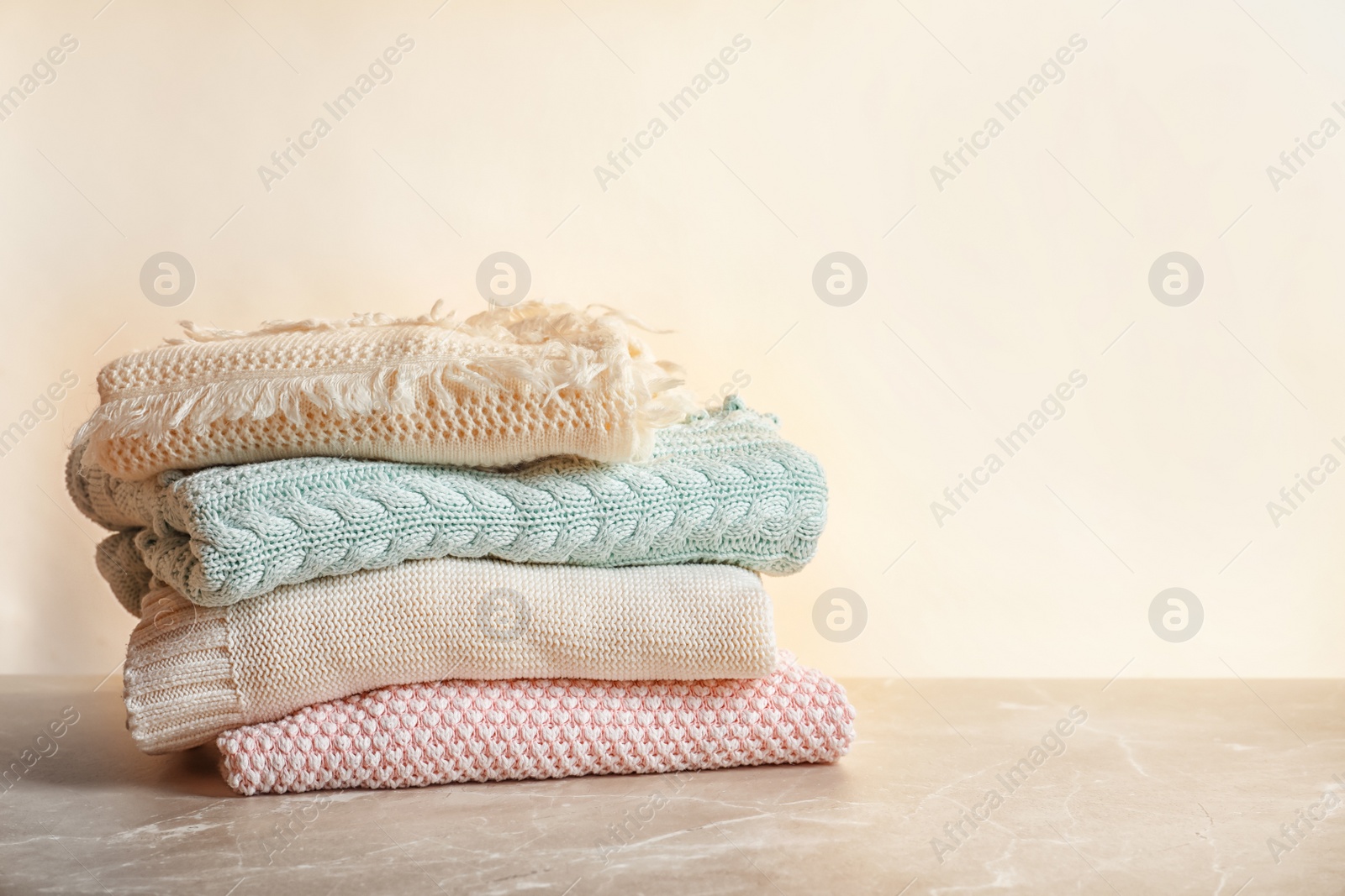 Photo of Stack of warm knitted clothes on table