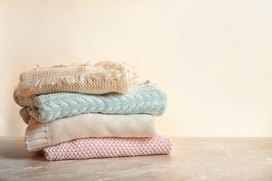 Photo of Stack of warm knitted clothes on table