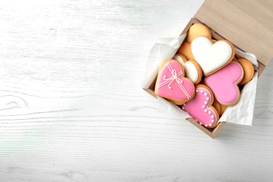 Photo of Decorated heart shaped cookies in wooden box and space for text on table, top view