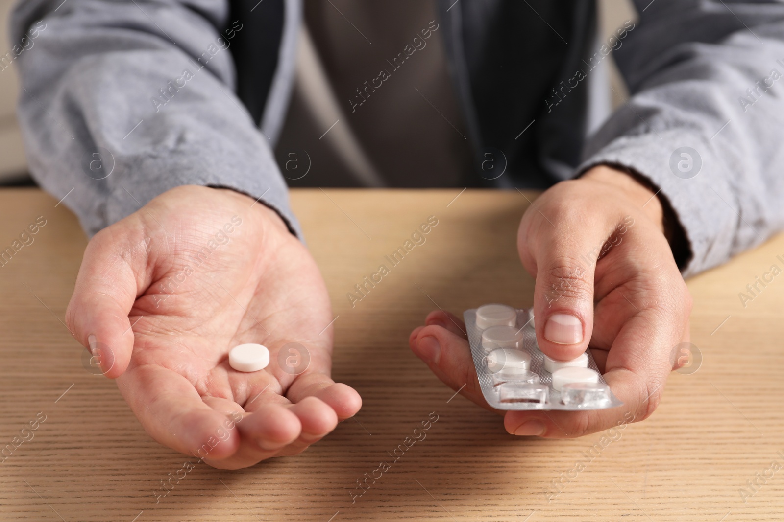 Photo of Man holding pills at wooden table, closeup