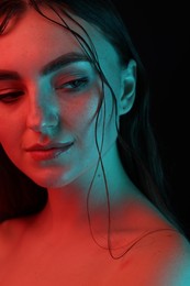 Photo of Portrait of beautiful woman in neon lights against black background, closeup