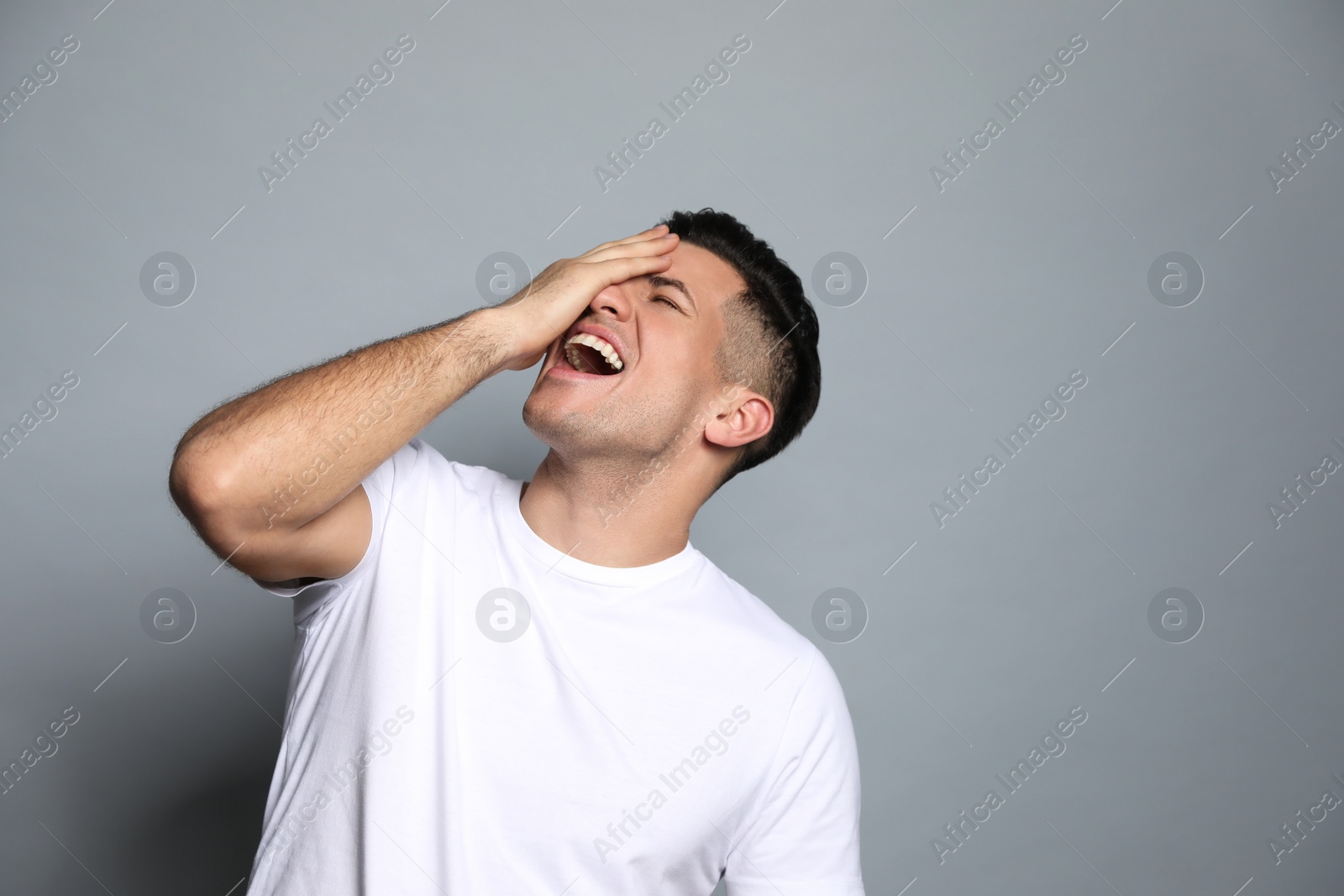 Photo of Handsome man laughing on grey background. Funny joke