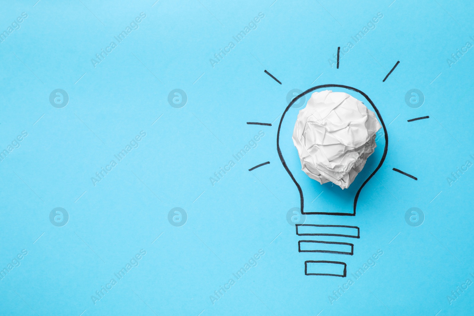 Photo of Idea concept. Light bulb made with crumpled paper and drawing on light blue background, top view. Space for text