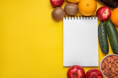 Photo of Notebook, fresh fruits and almonds on yellow background, flat lay with space for text. Low glycemic index diet