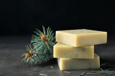 Handmade soap bars and fir branch on table