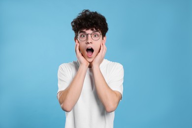 Photo of Portrait of shocked teenage boy wearing glasses on light blue background