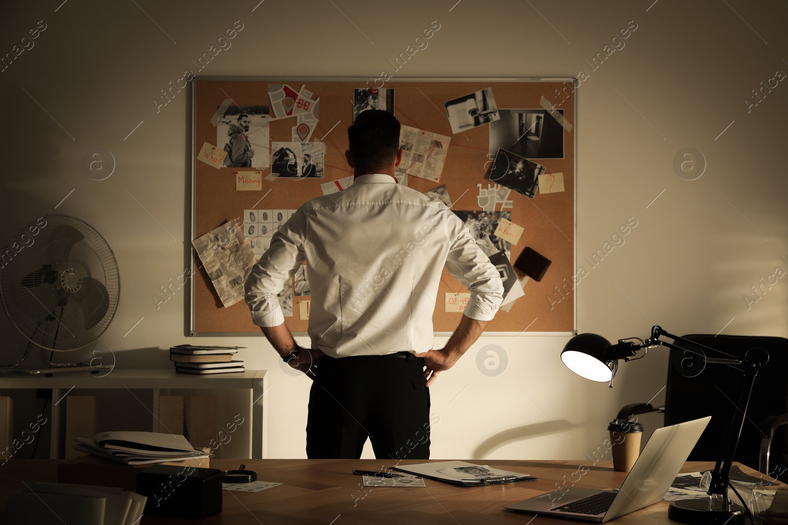 Photo of Detective looking at evidence board in office