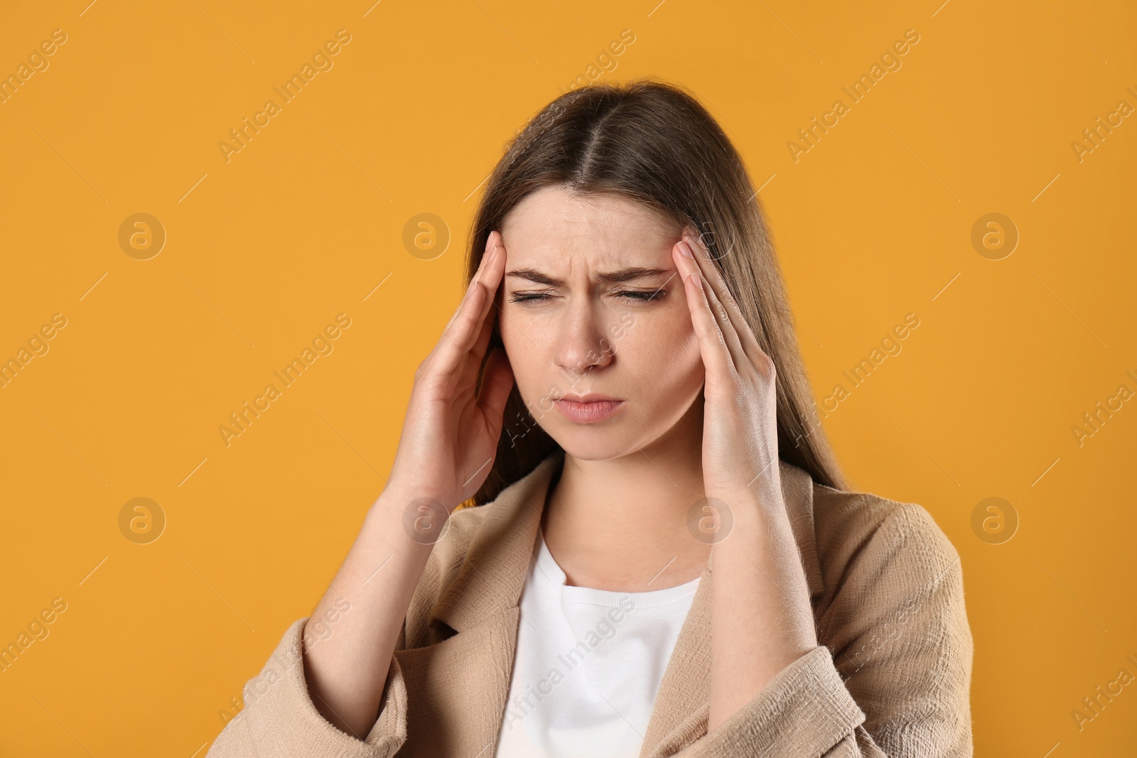 Photo of Young woman suffering from migraine on yellow background