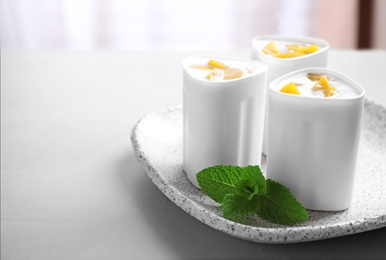 Plate with cups of peach yogurt on table, space for text. Multi cooker recipe