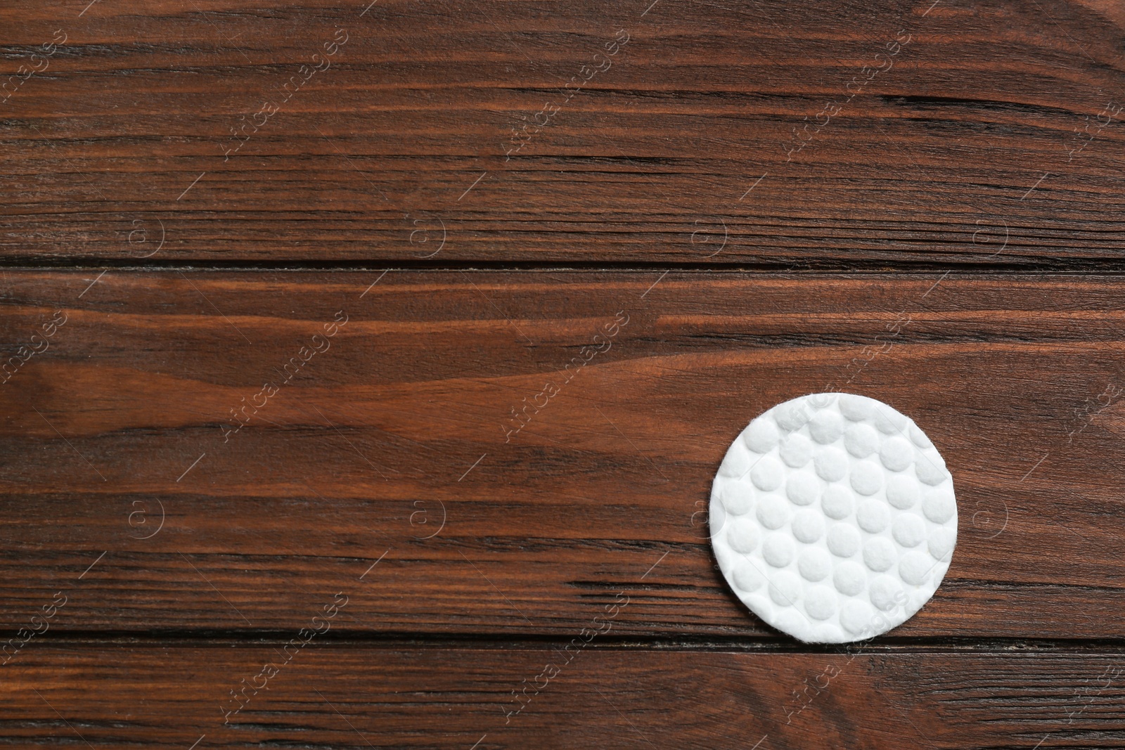 Photo of Cotton pad on wooden background, top view. Space for text