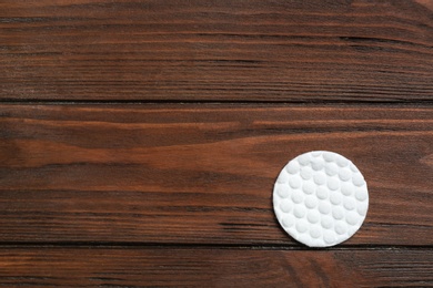 Cotton pad on wooden background, top view. Space for text