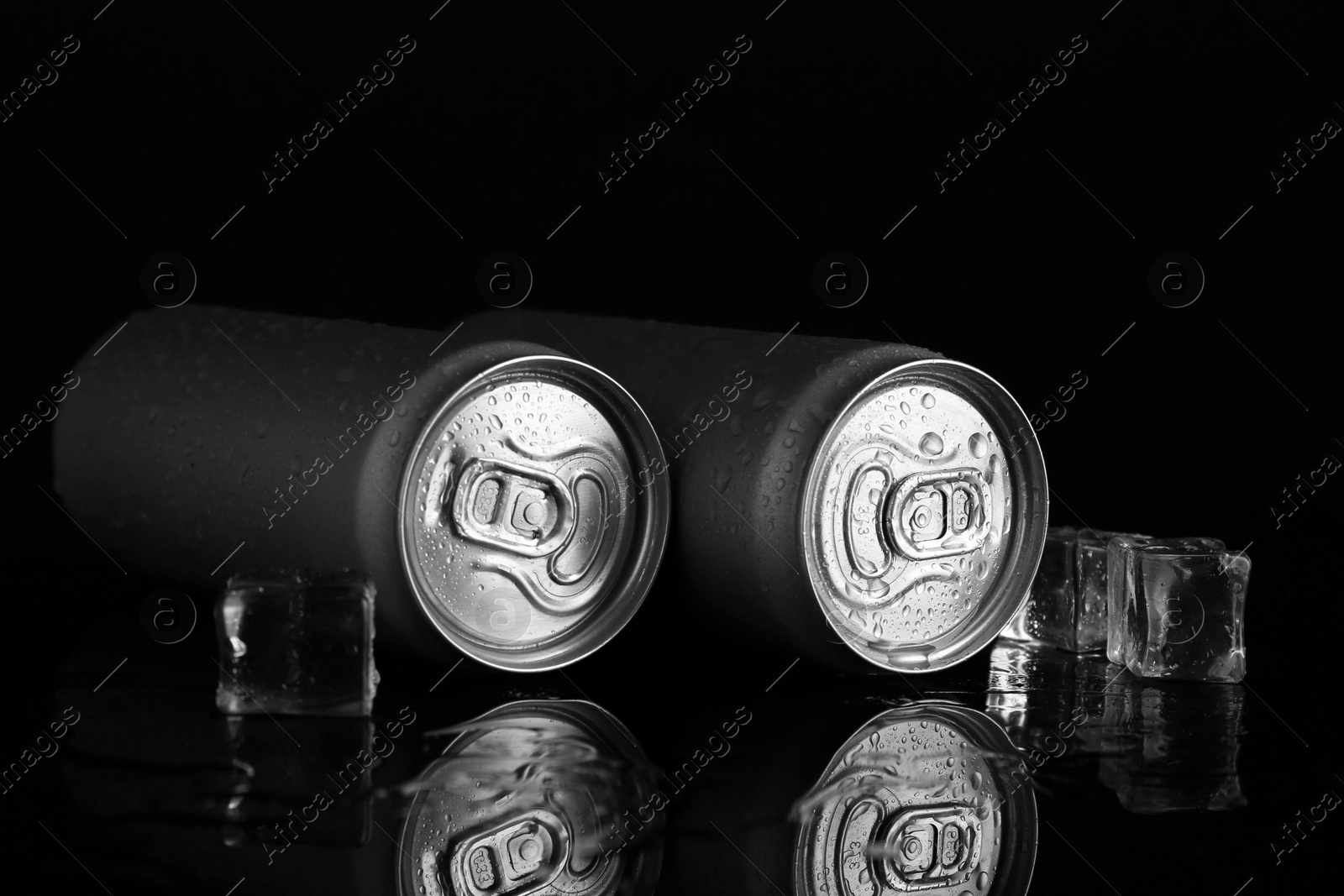 Photo of Energy drinks in wet cans and ice cubes on black background