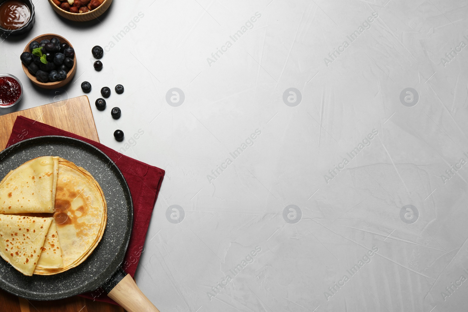 Photo of Delicious crepes with blueberries and mint on light grey table, flat lay. Space for text